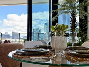 Mesa para cuatro personas dispuesta con vista despejada al horizonte de la ciudad a través de amplias ventanas.