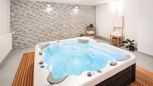 A modern bathroom with a freestanding hot tub, a wooden floor, a towel rack, and a radiator.