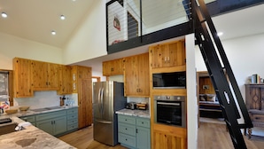 A modern kitchen with wooden cabinets, a stainless steel refrigerator, and a built-in oven.