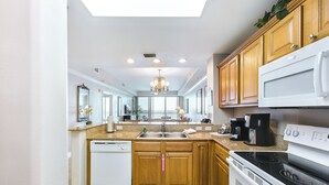 A modern kitchen with wooden cabinets, a white dishwasher, a stove, and a microwave. - Lake View Resort, 2 BR, 2 bath, sleeps 8, 2 MI to Disney with pool, balcony, gym (Orlando)