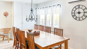 Un coin repas avec une table et des chaises en bois, un lustre et une grande horloge murale.