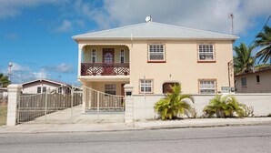 A two-story house with a balcony, a gated entrance, and a clear sky. - TRINITY BREEZE APARTMENT 1 (Christ Church)