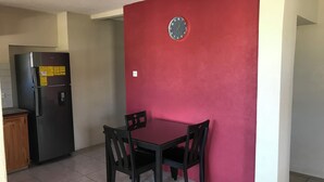 A dining area with a red accent wall, a clock, and a black refrigerator. - TRINITY BREEZE APARTMENT 1 (Christ Church)