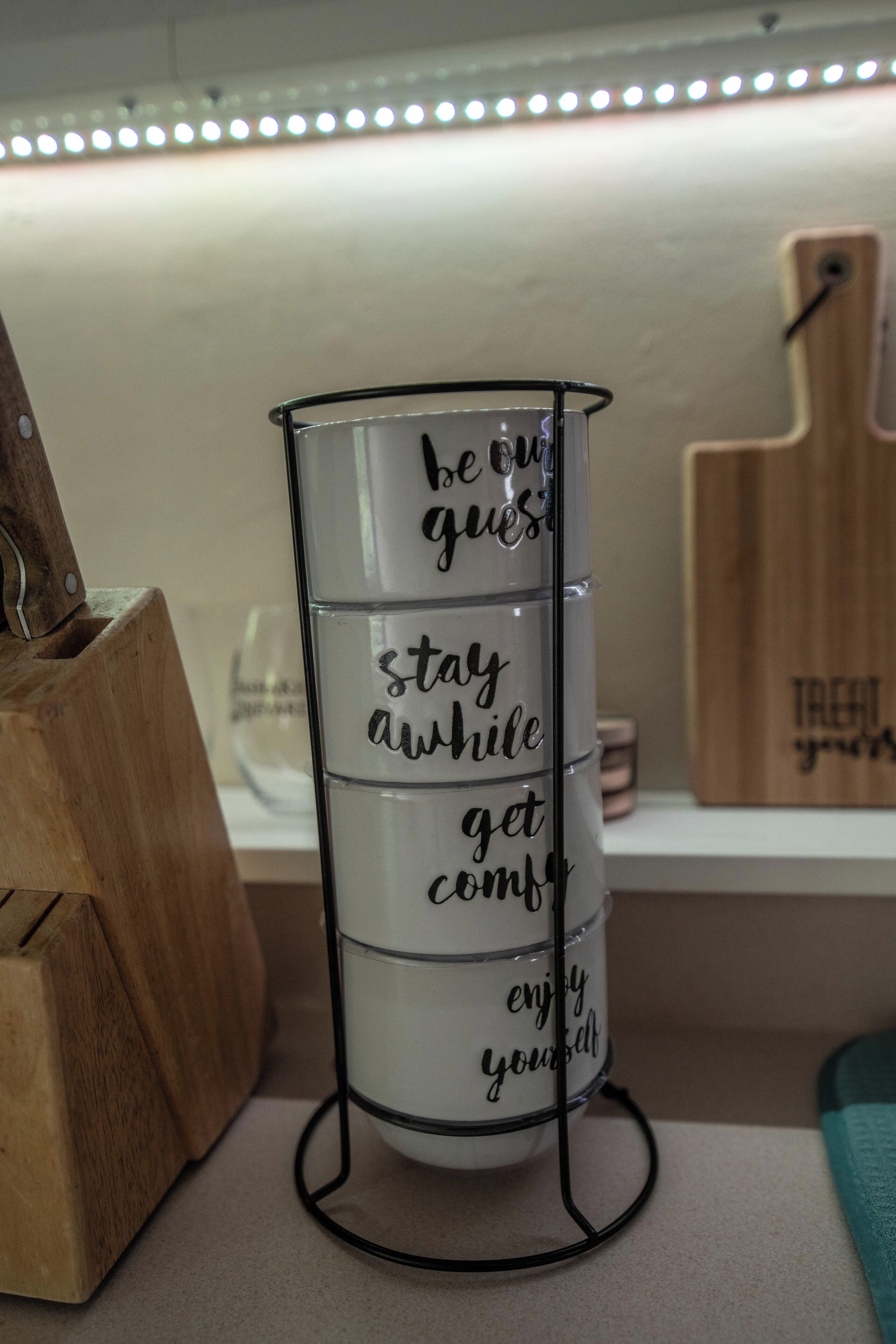 A stack of white mugs with motivational phrases on a metal stand.