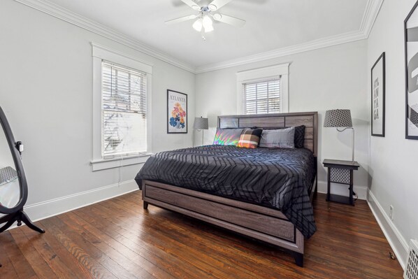 A bedroom with a bed, two windows, a ceiling fan, and a small table. - Family Getaway Near Zoo & Downtown Fun! Sleeps 10 (Atlanta)