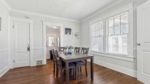 A dining area with a wooden table and chairs, white walls, and large windows with blinds. - Family Getaway Near Zoo & Downtown Fun! Sleeps 10 (Atlanta)