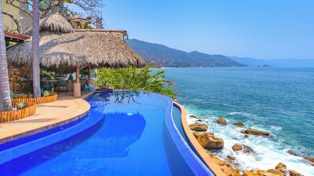 A infinity pool with a view of the sea and mountains.