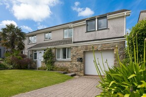 A two-story house with a stone facade, a garage, and a well-maintained lawn. - Ocean Parc - Sea Views/Pet Friendly (Carbis Bay)