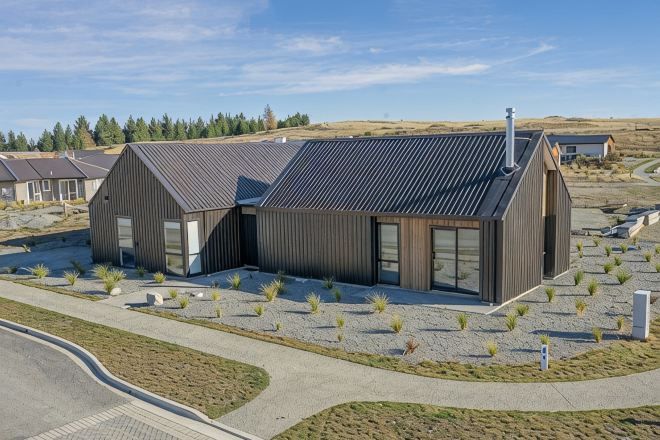 Un bâtiment moderne doté d’un toit en pente, de grandes fenêtres et d’une allée pavée.