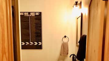 A narrow bathroom with a wooden door, a white sink, a towel rack, and a poster on the wall.