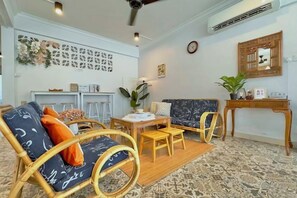 Une pièce comprenant un canapé, des fauteuils, une table à manger et une petite table sur laquelle est posée une plante.
