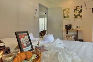 A hotel room with a bed, a framed picture, a basket with croissants, and a small table with a cup. - NewWALAI N3 Landed house near IMAGO KK CarGarage (Kota Kinabalu)