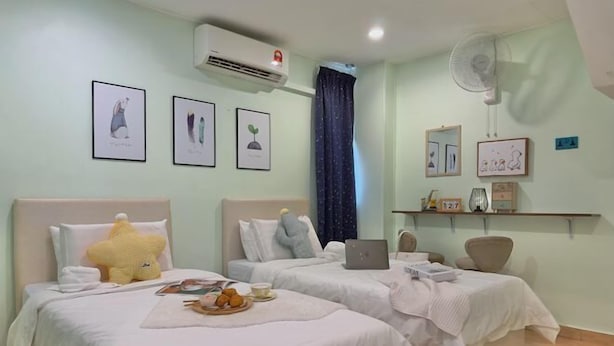 Habitación de hotel con dos camas, aire acondicionado, ventilador y obras de arte enmarcadas en las paredes.