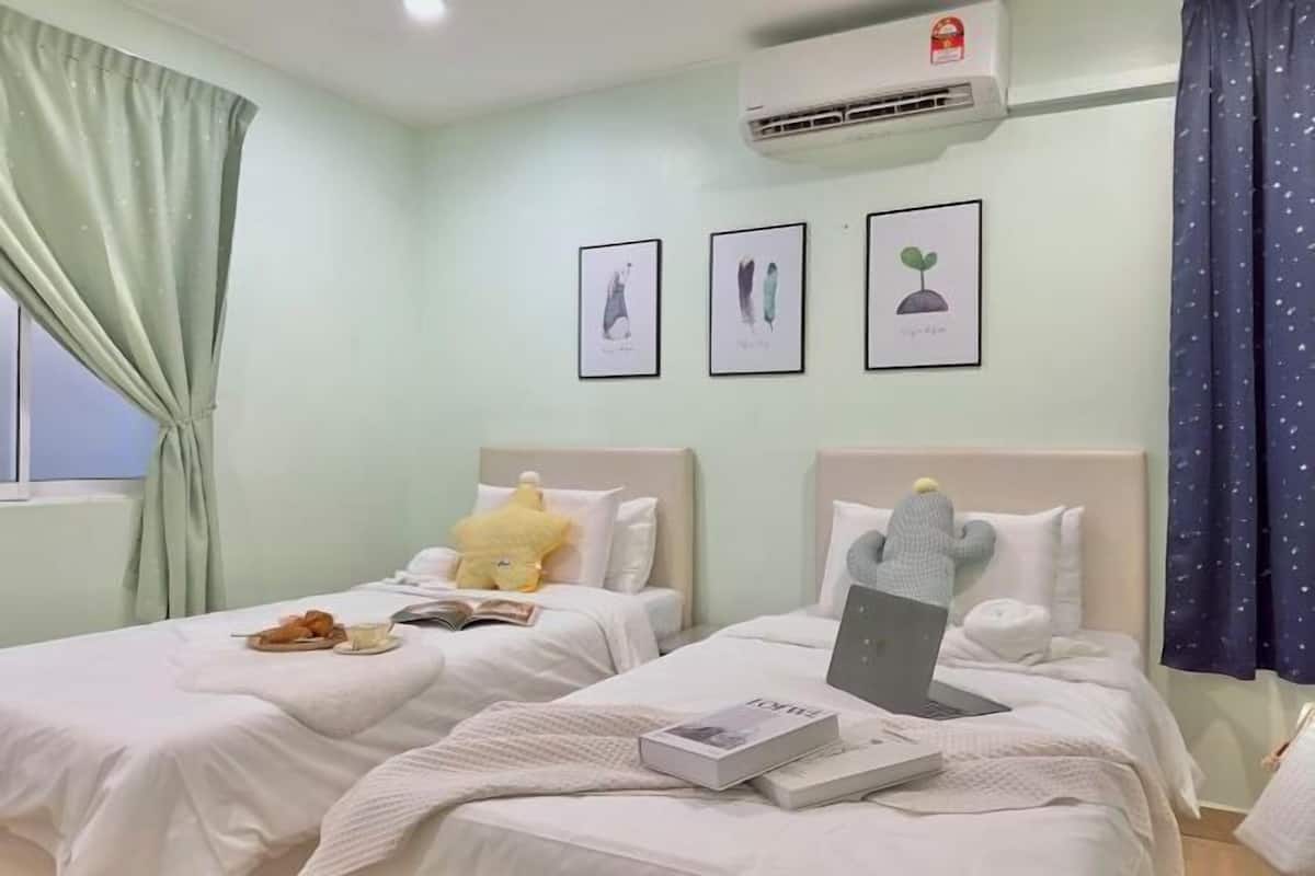 A hotel room with two beds, a window with curtains, an air conditioner, and framed artwork on the wall.