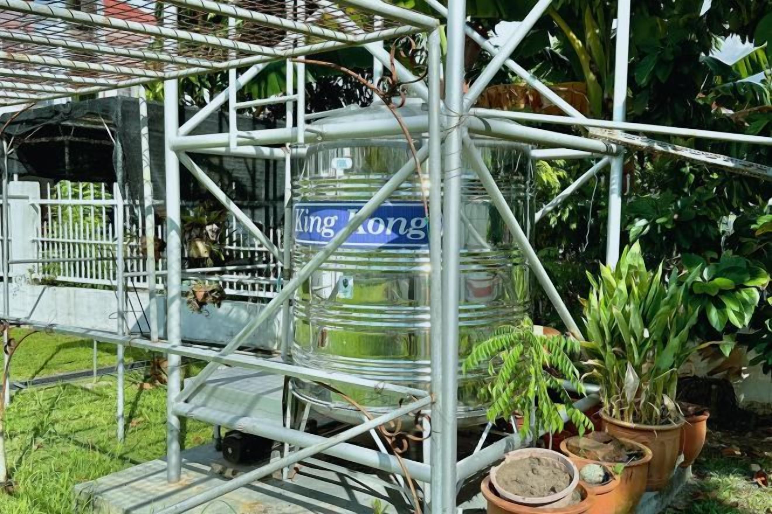 A metal structure with a large cylindrical object labeled 'King Kong' and potted plants around it.