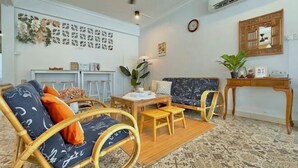 Una sala de estar con sofá, sillas, una mesita y un panel decorativo en la pared.
