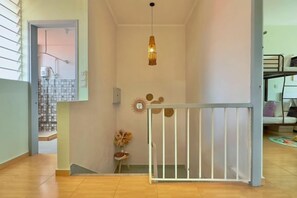 Una escalera con barandilla blanca, una lámpara colgante y una pequeña mesa con un florero.