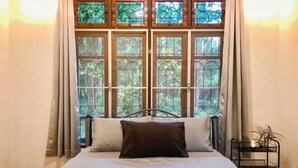 A bed with a headboard, a window with curtains, and a bedside table with a plant. - Silpasom ARTstay Suratthani (Phunphin)