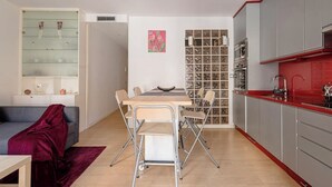 Ein kompakter Wohnraum mit Essbereich, Küchenzeile und einer Couch mit roter Decke.