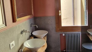 Ein Badezimmer mit Holzbalkendecke, zwei Waschbecken mit runden Becken, einem Spiegel und einem Fenster.