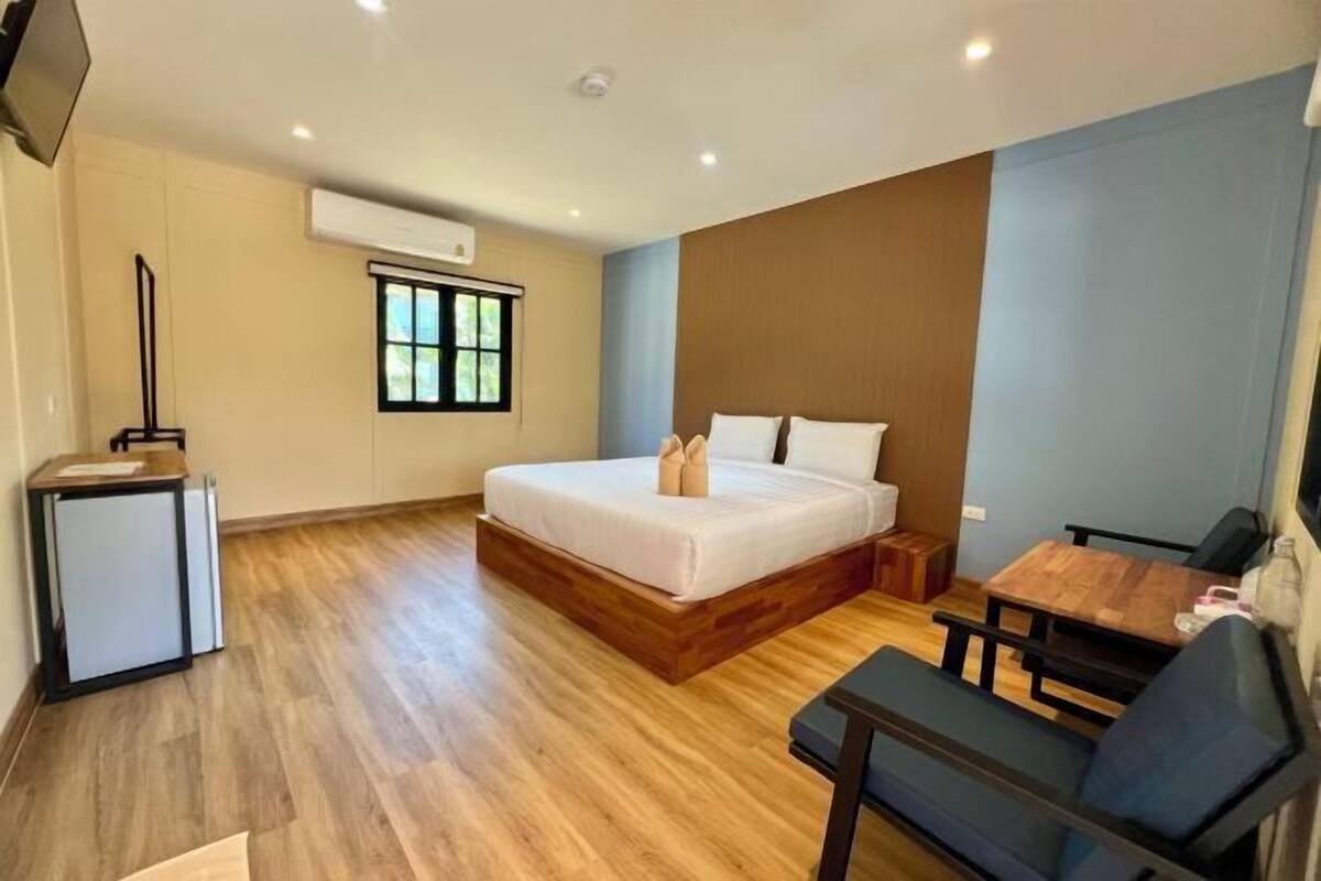 A hotel room with a bed, a desk, a chair, a TV, and a window.