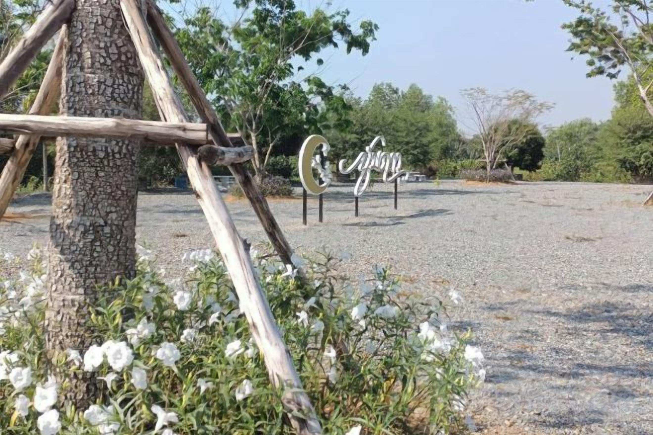 A gravel area with a wooden structure, a tree, and a sign with the word 'spring'.