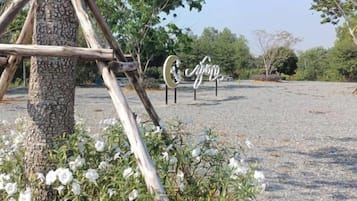 A gravel area with a wooden structure, a tree, and a sign with the word 'spring'.
