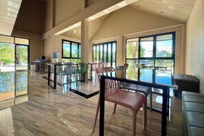 A spacious indoor area with a pool, multiple tables, and chairs arranged for dining or socializing. - Napdown Resort Trat (Trat)