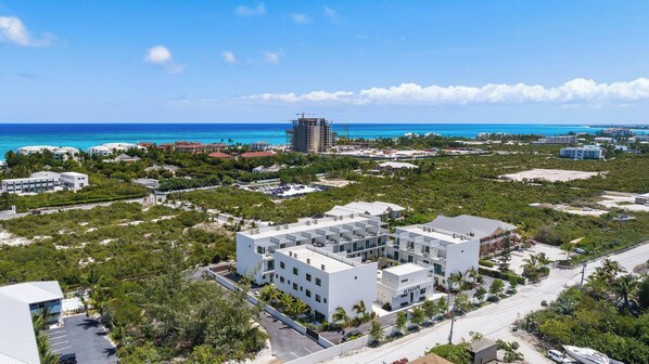 A coastal hotel with multiple buildings, a parking area, and a view of the ocean. - New Modern 3Bed 3.5 Bath Townhome #14 (Grace Bay)