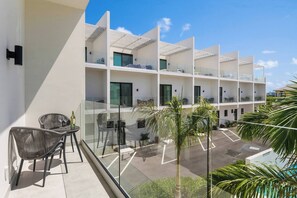 A modern hotel with a balcony, outdoor seating, and a view of the parking area. - New Modern 3Bed 3.5 Bath Townhome #14 (Grace Bay)