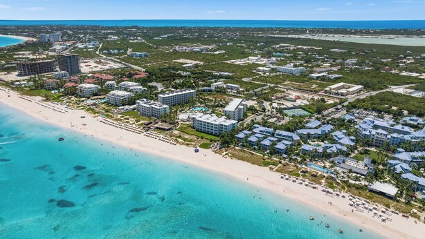 An aerial view of a coastal resort area with beachfront properties, a sandy beach, and clear blue waters.