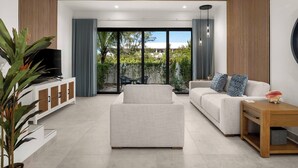 A modern living room with a sofa, a coffee table, and a TV on a white cabinet.