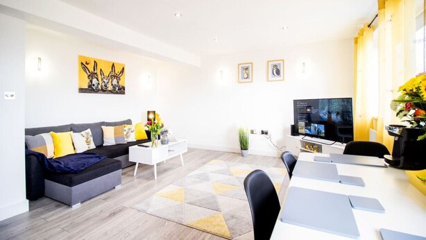 Ein modernes Wohnzimmer mit einem grauen Sofa, einem weißen Couchtisch und einem Fernseher auf einem Lowboard.