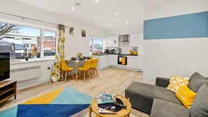 Un apartamento moderno con comedor, cocina, sala de estar y un ventanal con vista a la ciudad.
