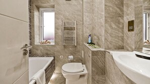 Un baño moderno con bañera, inodoro y perchero para toallas.