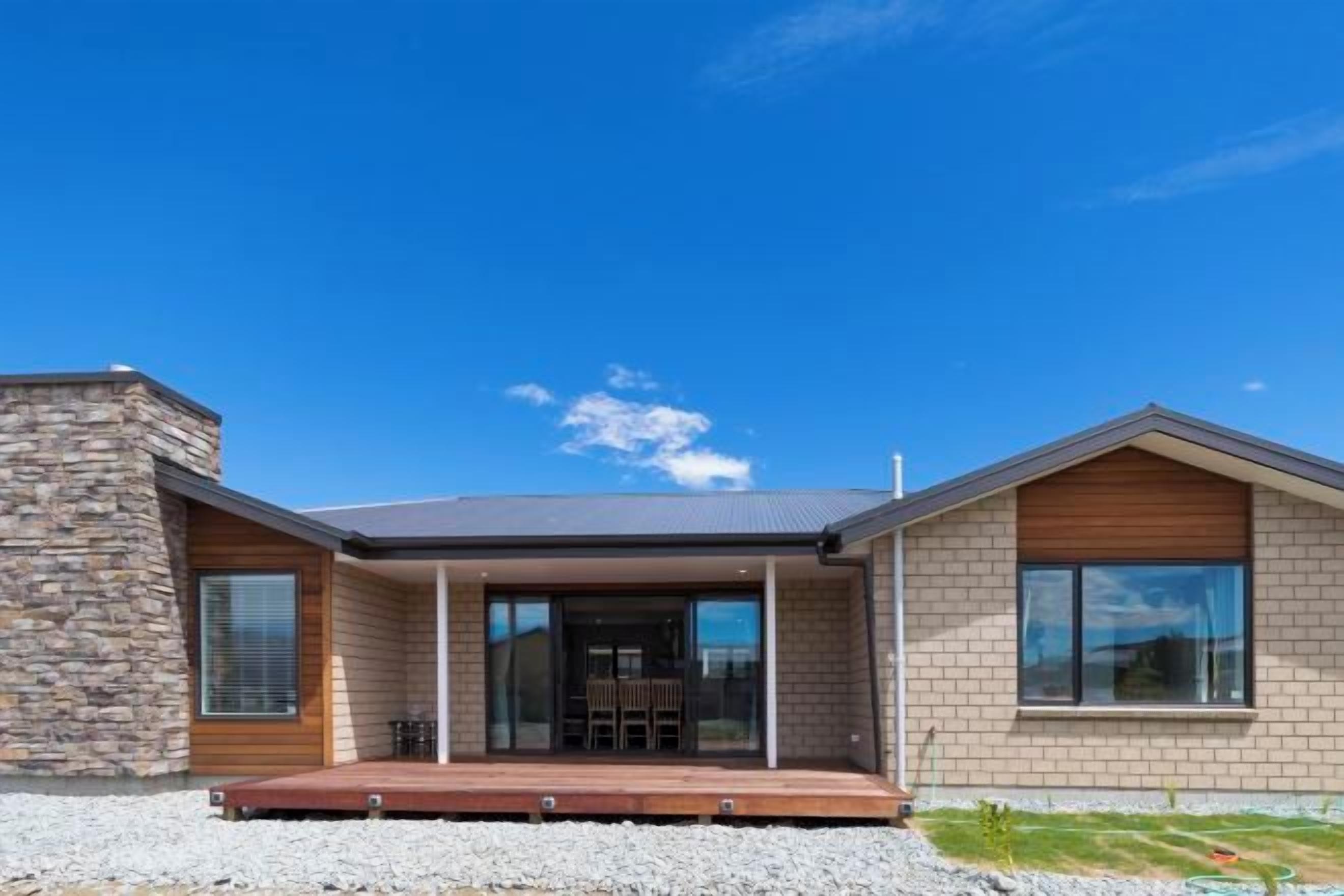 A modern house with a stone facade, a flat roof, and a front porch.