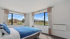 Ein Schlafzimmer mit Bett, großen Fenstern und einer Heizung.