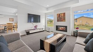 Ein modernes Wohnzimmer mit Kamin, Flachbildfernseher und einer Couch.