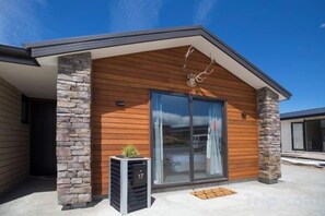 A modern building with a stone facade, large glass doors, and a small planter. - Hunter Hunter (Lake Tekapo)