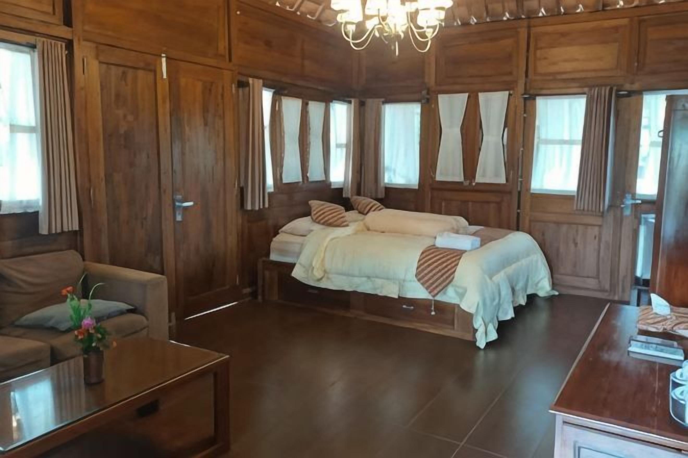 Ein Zimmer aus Holz mit einem Bett, einem Sofa und einem Tisch.