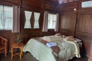 Una stanza in legno con un letto, tende e un tavolino con un vaso.