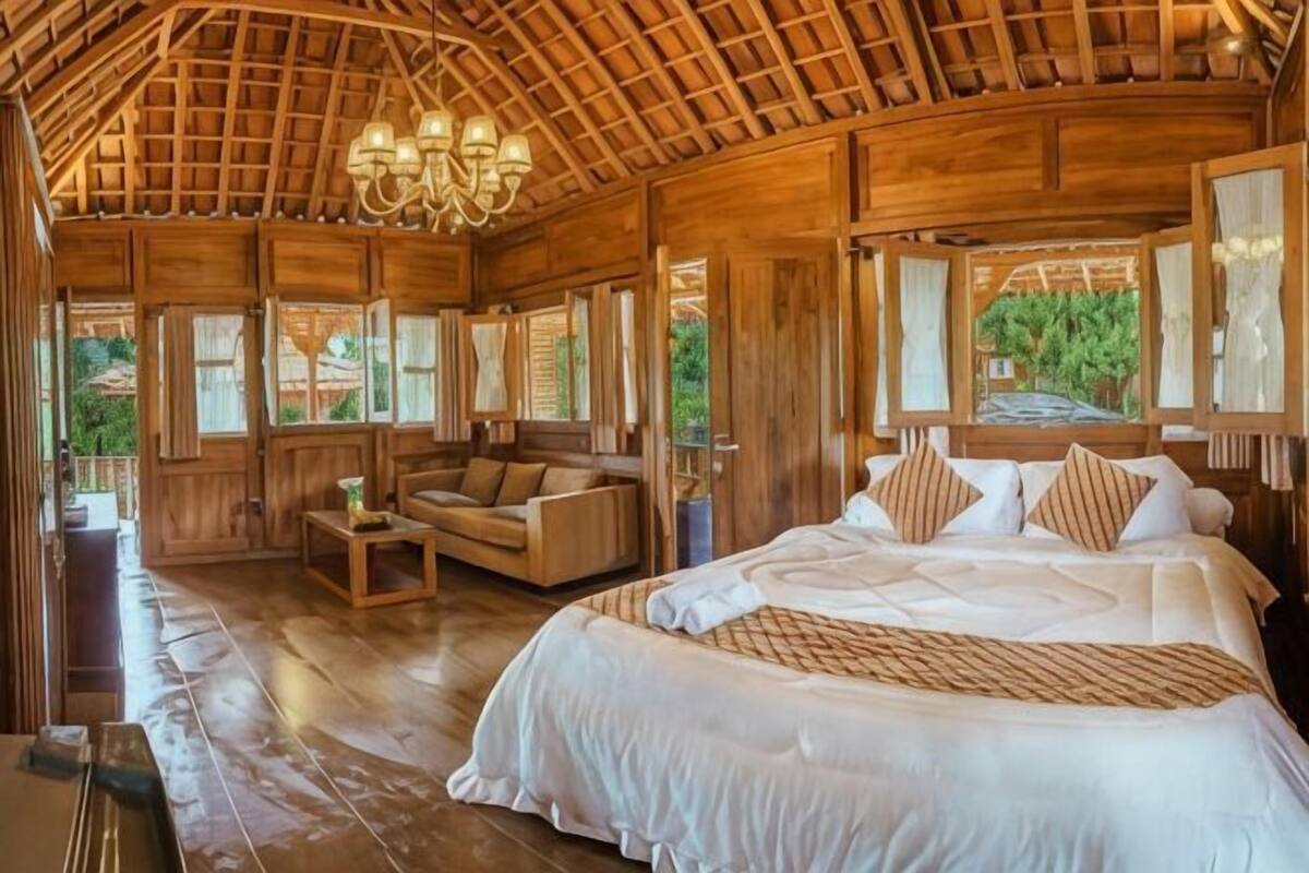 Ein Zimmer aus Holz mit einem Bett, einem Sofa und einer Chandelier.