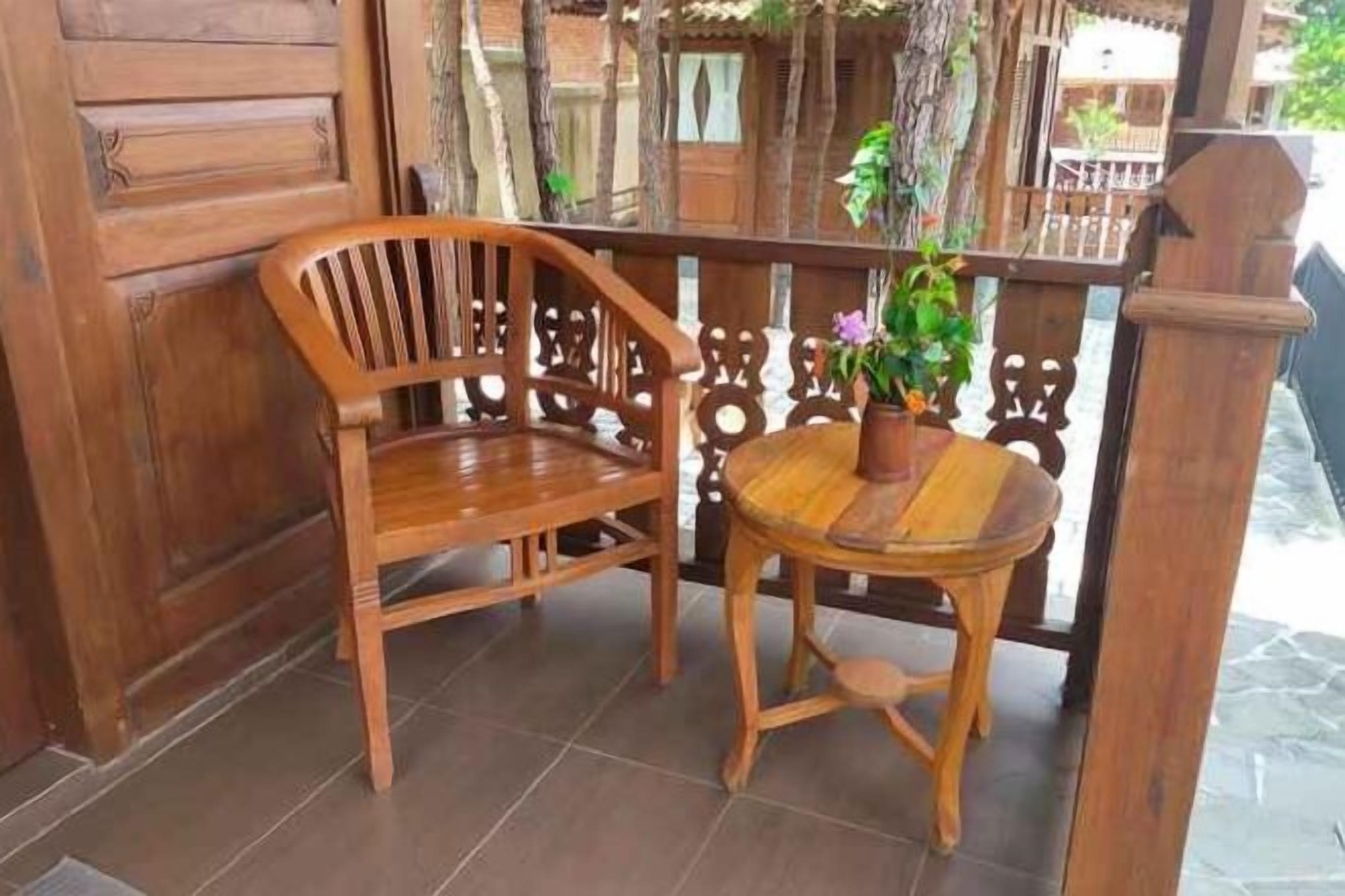 A wooden chair and table set on a tiled floor, with a wooden railing and a potted plant.