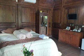 Camera da letto con un letto grande, pannelli in legno, una cassettiera, uno specchio e una televisione.