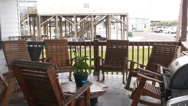 Ein überdachter Außenbereich mit Holzstühlen und einem Grill.