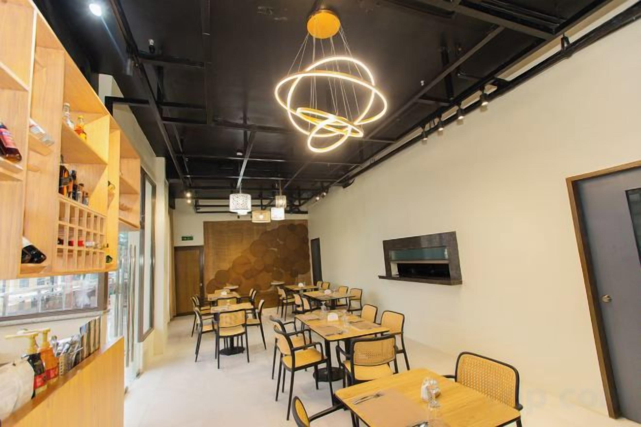 A modern dining area with tables and chairs, a bar area with shelves, and a unique circular light fixture.