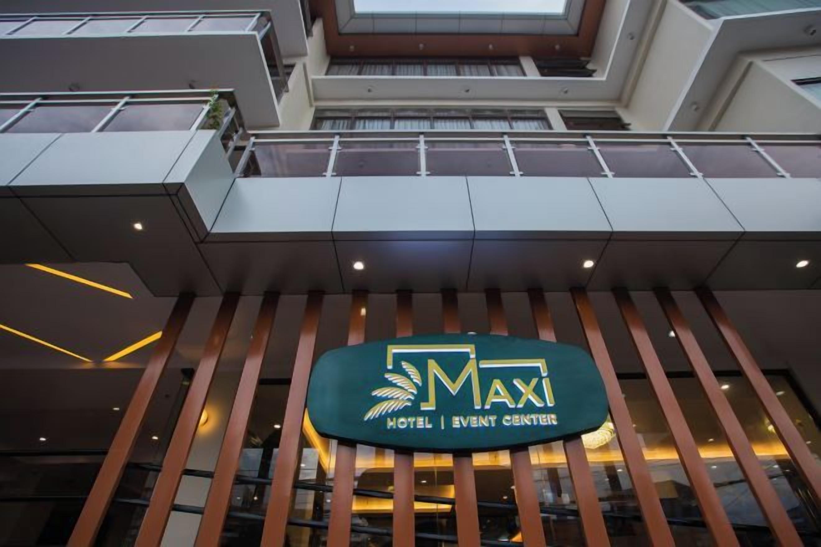 A hotel entrance with a sign that reads 'MAXI HOTEL | EVENT CENTERER'.