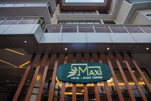 En hotelindgang med et skilt, der viser 'MAXI HOTEL | EVENT CENTERER'.