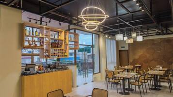 A modern cafe with a bar area, seating arrangements, and a view through the glass wall.