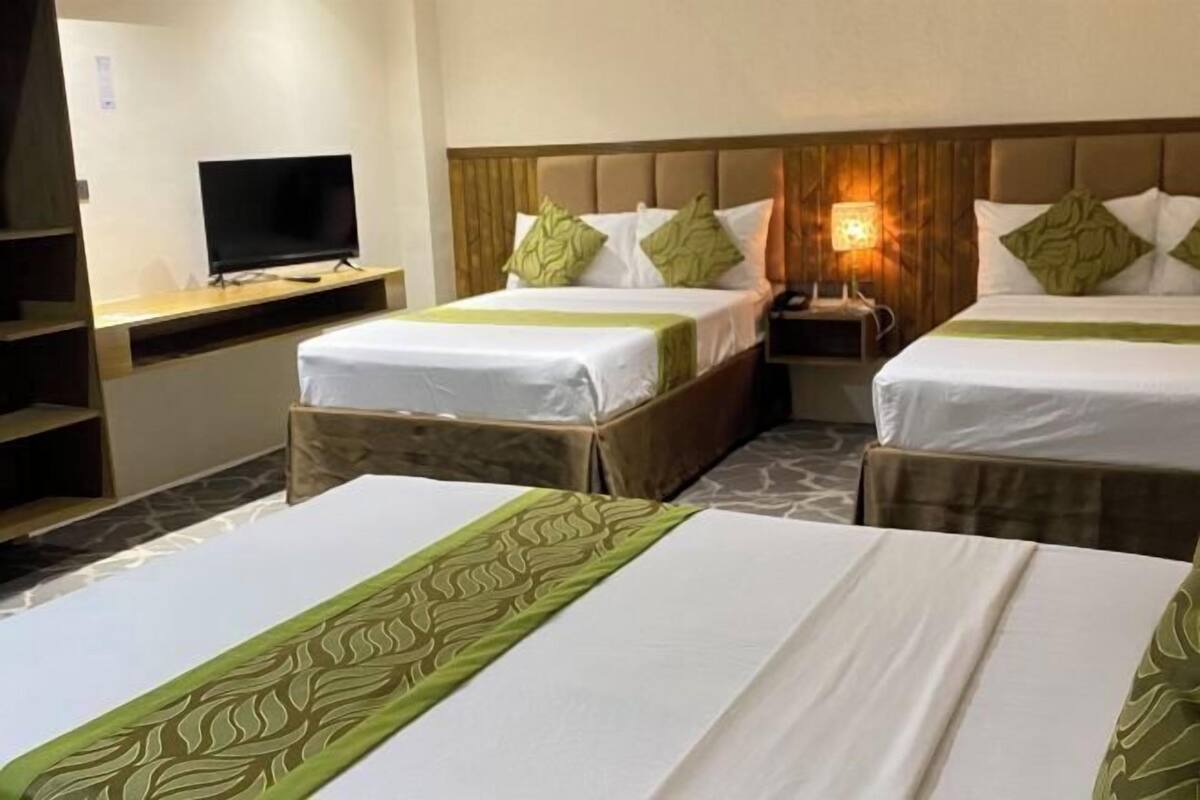 A hotel room with two beds, a TV, and a desk.